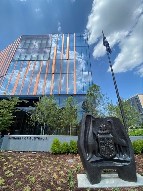 Embassy in background with statue of Australian crest in foreground.